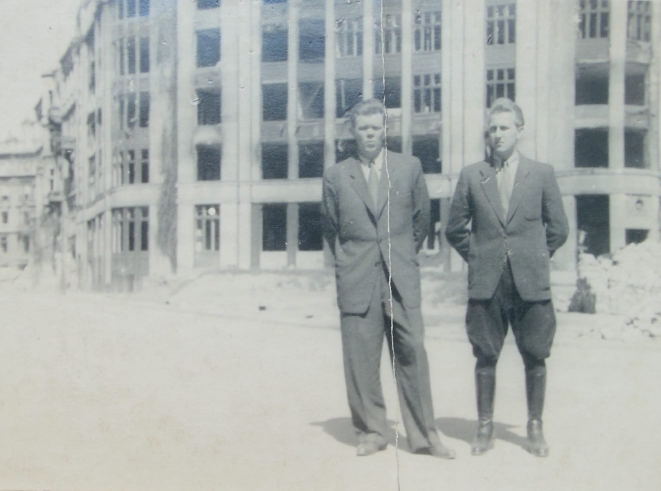 Stanisław Jędrasik (z lewej) w towarzystwie niezidentyfikowanego mężczyzny, na tle wypalonego gmachu – Warszawa po wojnie. Ze zbiorów prywatnych.