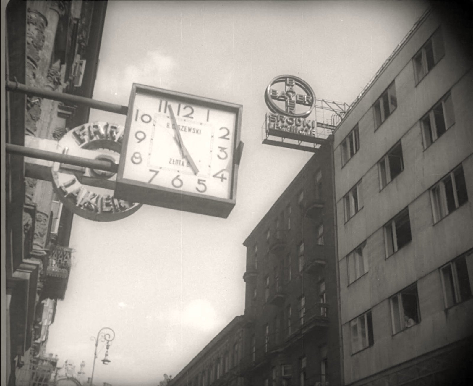 Ulica Złota tuż przed Godziną „W”, 1 sierpnia 1944 roku. Zegar
uliczny wskazuje za pięć piątą; po prawej gmach Złotej 7/9 z neonem
Bayera na attyce. Kadr filmowy ze zbiorów Filmoteki Narodowej.